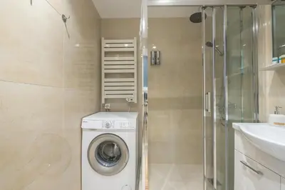 a bathroom with a washing machine and a sink at The 