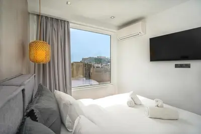 a bedroom with a white bed and a large window at Stylish Living-Parthenon in Athens