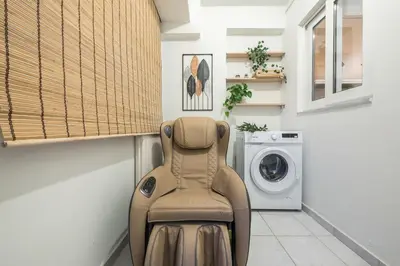 a chair in a laundry room with a washing machine at Parthenon Dream, breathtaking views with massage chair in Athens