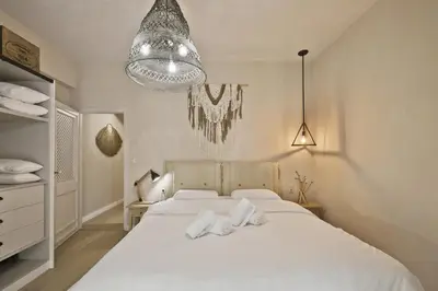 a bedroom with two white beds and a chandelier at Stylish Apartment at Pagrati in Athens