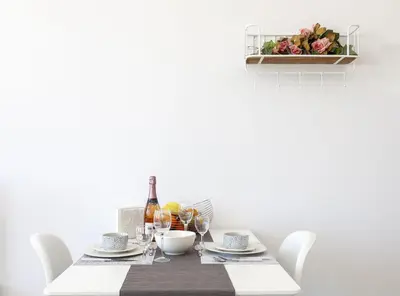 a dining table with white chairs and a bottle of wine at Fedias Luxury flat Psyrri square in Athens