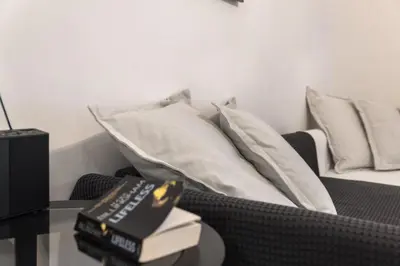 a couch with pillows and a table with books on it at Amazing apartment 2 min to Acropolis in Athens