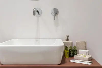 a white sink in a bathroom with bottles on a counter at Acropolis White Key Residence in Athens
