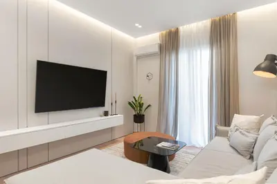 a living room with a couch and a tv on a wall at Acropolis White Key Residence in Athens