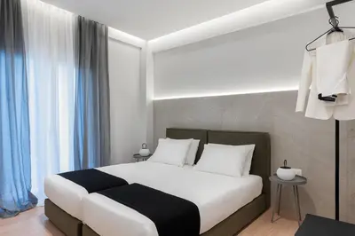 a bedroom with a bed with white sheets and blue curtains at Acropolis White Key Residence in Athens