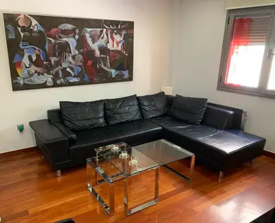 a living room with a black couch and a glass table at Olvias Apartment in Athens