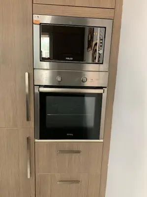 a microwave oven sitting inside of a wooden cabinet at Olvias Apartment in Athens