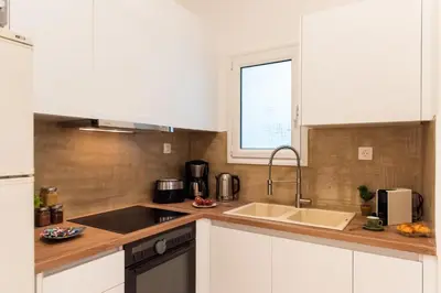 a kitchen with white cabinets and a sink and a window at Blue Ark Comfort near Acropolis in Athens