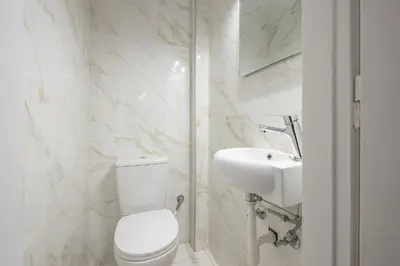 a white bathroom with a toilet and a sink at Victoria Majestic Suites Apartments in Athens