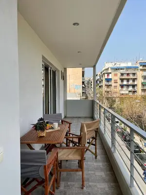 a balcony with a wooden table and chairs on it at Ageliki's Athens Apartment in Athens