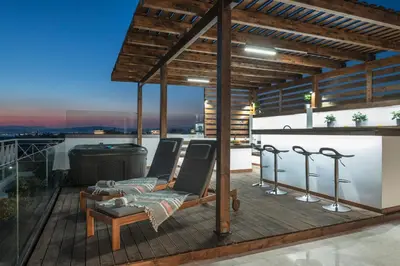 a deck with chairs and a grill on a rooftop at Bright 3bdr Apt with Roofgarden, Jacuzzi in Athens