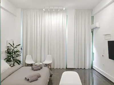 a bedroom with a bed and two chairs and a tv at KYMA Apartments - Athens Acropolis 22 in Athens
