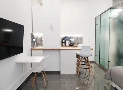a white kitchen with a counter and two stools at KYMA Apartments - Athens Acropolis 22 in Athens