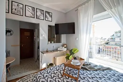 a bedroom with a bed and a kitchen with a window at Athenian Sun-Kissed Penthouse with huge Balcony! in Athens