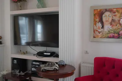 a living room with a tv and a table and a red chair at Glifada Calm Luxury Flat One in Athens