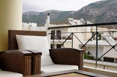a wicker chair sitting on a balcony with a view at Glifada Calm Luxury Flat One in Athens