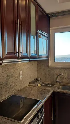 a kitchen with wooden cabinets and a sink and a window at Glifada Calm Luxury Flat One in Athens