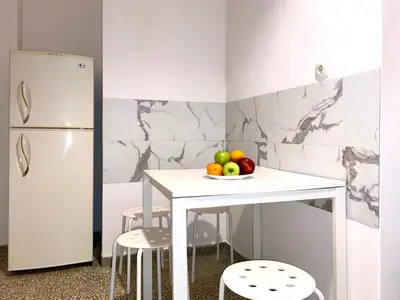 a kitchen with a table with a plate of fruit and a refrigerator at Kallithea's breeze in Athens