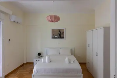 a white bedroom with a white bed and a cabinet at Bright and Spacious 2-bedroom Apartment in Athens in Athens