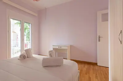 a white bedroom with a bed and a window at Bright and Spacious 2-bedroom Apartment in Athens in Athens