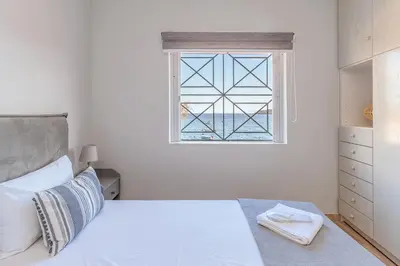 a white bedroom with a bed and a window at Pallas in Keratea