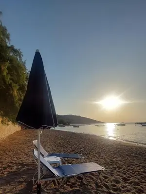 a beach chair and an umbrella on a beach at Pallas in Keratea