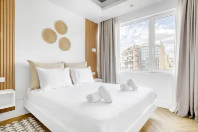 a white bedroom with a large white bed with towels on it at Kallirrois 89 Suite in Athens