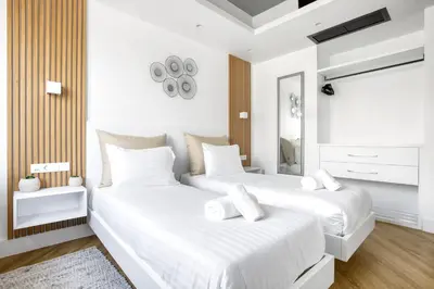 two beds in a white bedroom with a mirror at Kallirrois 89 Suite in Athens