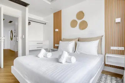 a white bedroom with a large white bed with white pillows at Kallirrois 89 Suite in Athens