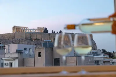 two glasses of white wine in front of a building at Acropoli's balcony in Athens