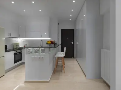 a white kitchen with a counter and a stool at Newly Renovated Apartment in the Heart of Athens in Athens