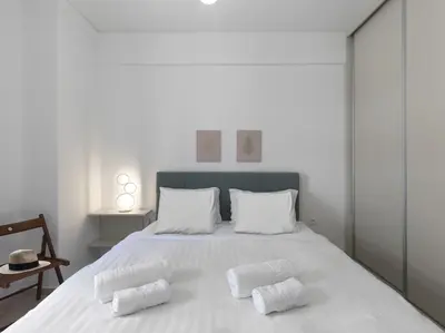a white bedroom with a large white bed with two pillows at Newly Renovated Apartment in the Heart of Athens in Athens