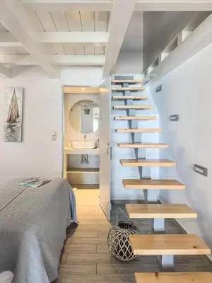 a spiral staircase in a room with a bed at Pallas Seaside 1 in Athens
