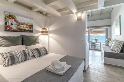 a white bedroom with a bed and a living room at Pallas Seaside 2 in Athens