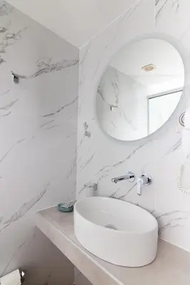 a white bathroom with a sink and a mirror at Dunlin Hotel in Athens