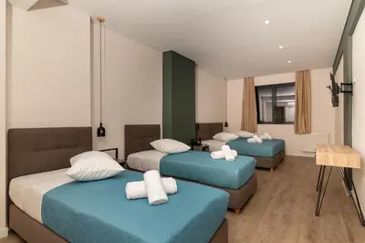 a hotel room with three beds and two chairs at Dunlin Hotel in Athens