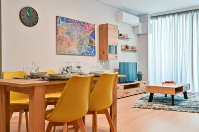 a dining room with a wooden table and yellow chairs at Beautiful new apartment 5 min from Piraeus Port (A2) in Piraeus