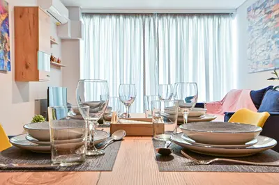 a dining room table with plates and wine glasses at Beautiful new apartment 5 min from Piraeus Port (A2) in Piraeus