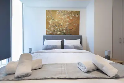 a bedroom with a large white bed with a painting at Waylink Residences - Piraeus Port SPT in Piraeus