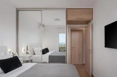 a bedroom with a bed and a tv and a mirror at Athenian Riviera Sea View Penthouse in Vari