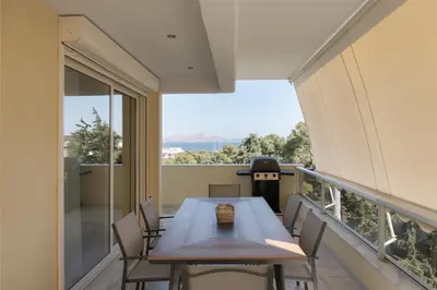 a balcony with a wooden table and chairs and a view at Athenian Riviera Sea View Penthouse in Vari