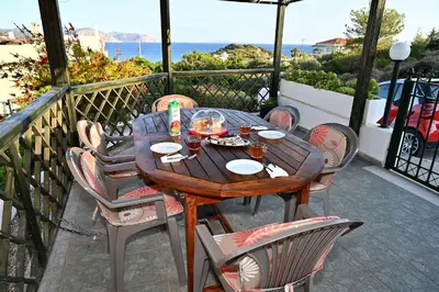a wooden table and chairs on a balcony with the ocean at Melrose maisonette by the sea in Anavissos