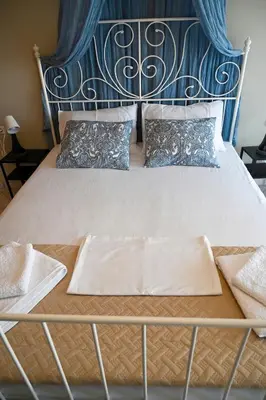 a bed with a blue headboard and pillows on it at Melrose maisonette by the sea in Anavissos