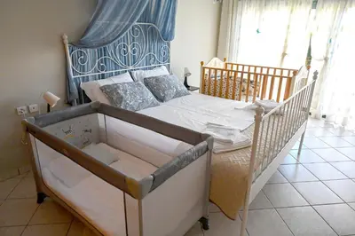 a baby crib in a bedroom with a bed at Melrose maisonette by the sea in Anavissos