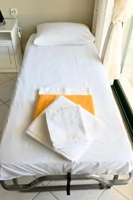 a bed with white sheets on it in a room at Melrose maisonette by the sea in Anavissos