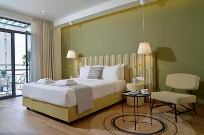 a bedroom with a large bed and a chair at Alva Athens Hotel in Athens