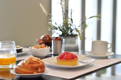 a table with plates of pastries and a glass of orange juice at Alva Athens Hotel in Athens