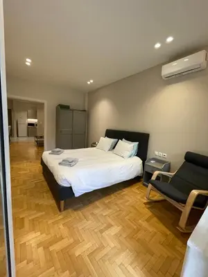 a bedroom with a large white bed and a chair at Optimal Point - Spacious Koukaki Apt in Athens
