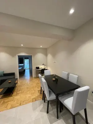 a dining room with a black table and white chairs at Optimal Point - Spacious Koukaki Apt in Athens