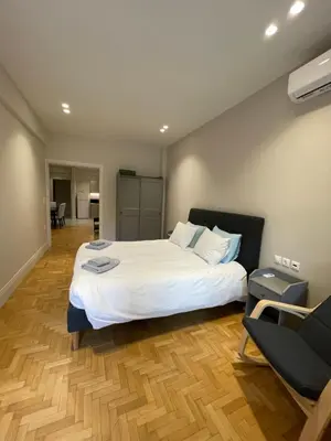 a bedroom with a large white bed and a chair at Optimal Point - Spacious Koukaki Apt in Athens